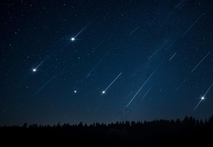 klarer Nachthimmel über einem Wald mit mehreren Sternschnuppen